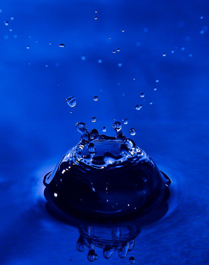 Stunning Macro Wallpaper: Water Droplet Splash with Blue Background