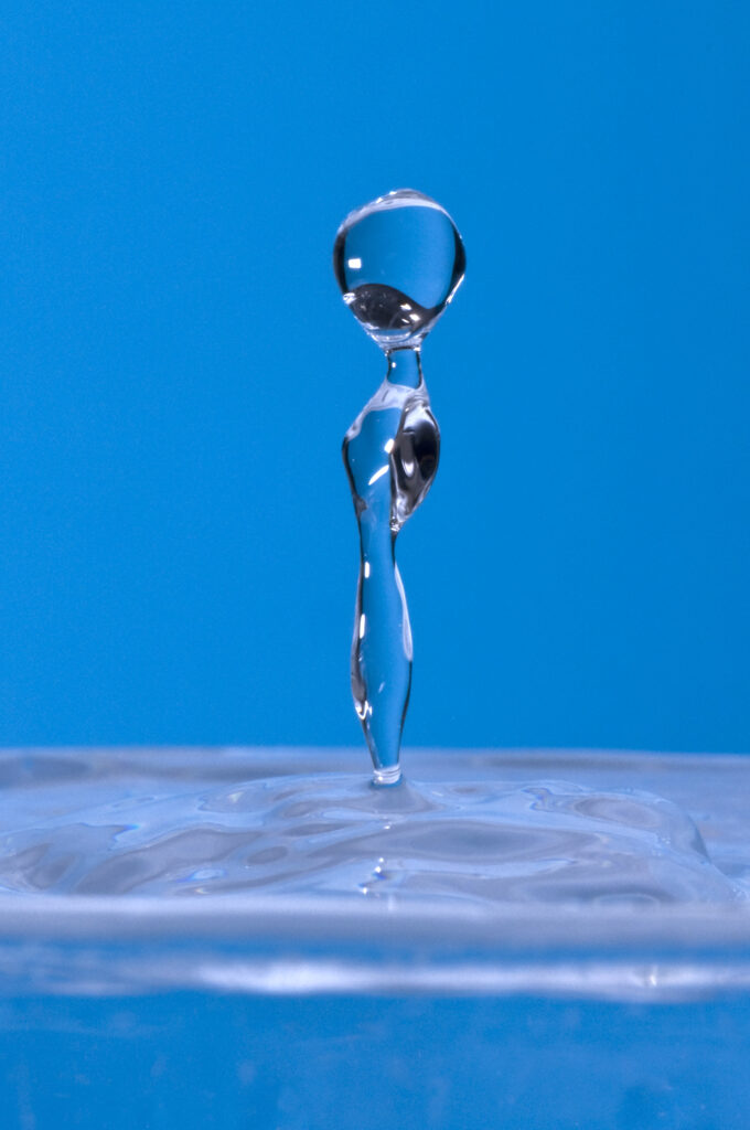 Stunning Macro Wallpaper: Water Droplet in Motion on Blue Background