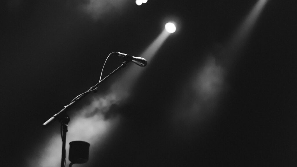 Spotlight Microphone: Poised Against Dramatic Black & White Background Wallpaper
