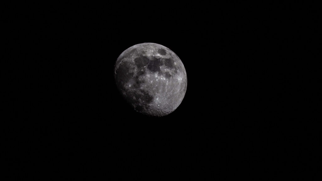 Detailed Moon craters and textures against a rich black space background wallpaper.