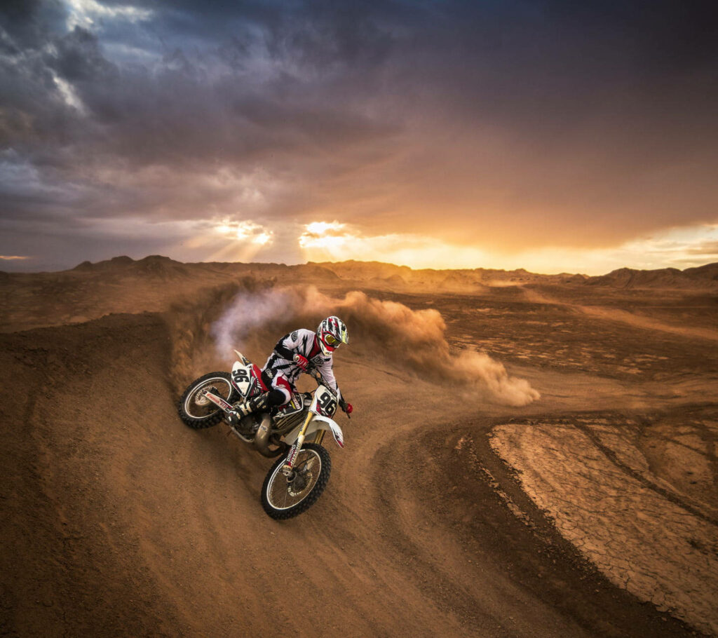 Stunning Motocross Wallpaper: Rider Drifting at Sunset in Desert