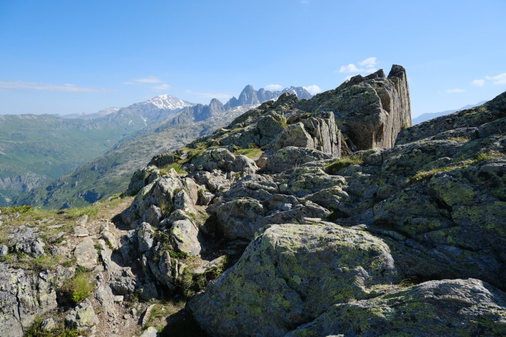 Stunning mountain landscape with jagged rocks green valleys and snow-capped peaks under blue sky Wallpaper