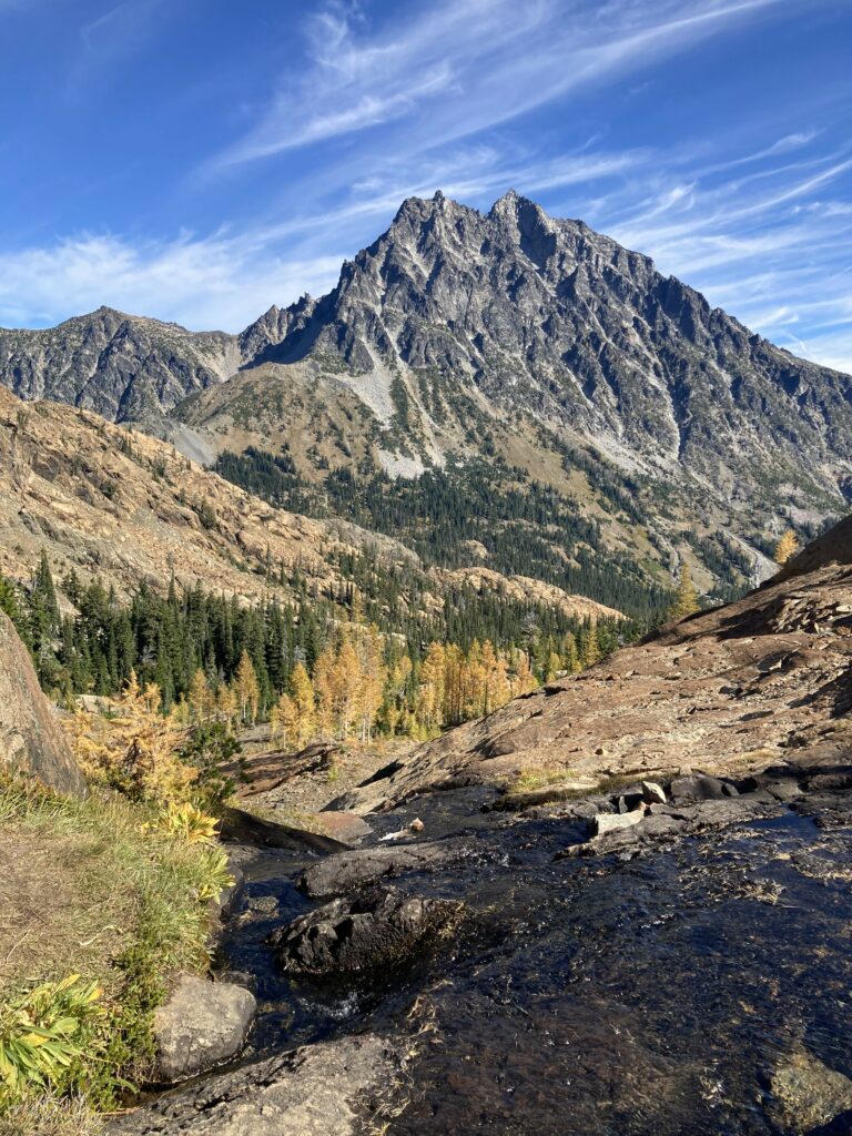 Mountain landscape with rugged peaks clear river smooth stones and golden autumn trees wallpaper background
