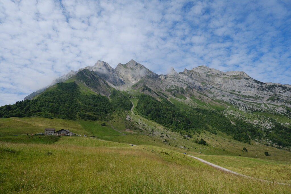 Mountain landscape with rocky peaks green valleys scattered forests under blue partly cloudy sky Wallpaper