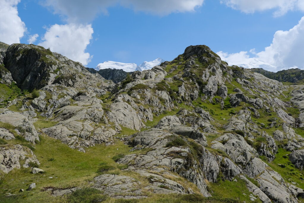 Stunning mountain landscape with rugged rocks green grass and bright blue sky with clouds wallpaper