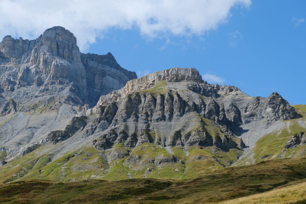 Mountainous landscape with rugged rocks rolling green slopes and bright blue sky wallpaper background