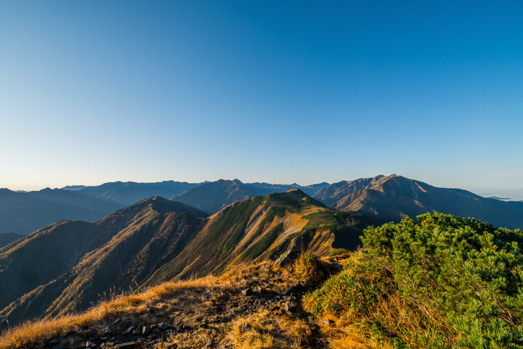 High-definition mountain landscape wallpaper with rugged rocks green bushes and clear blue sky