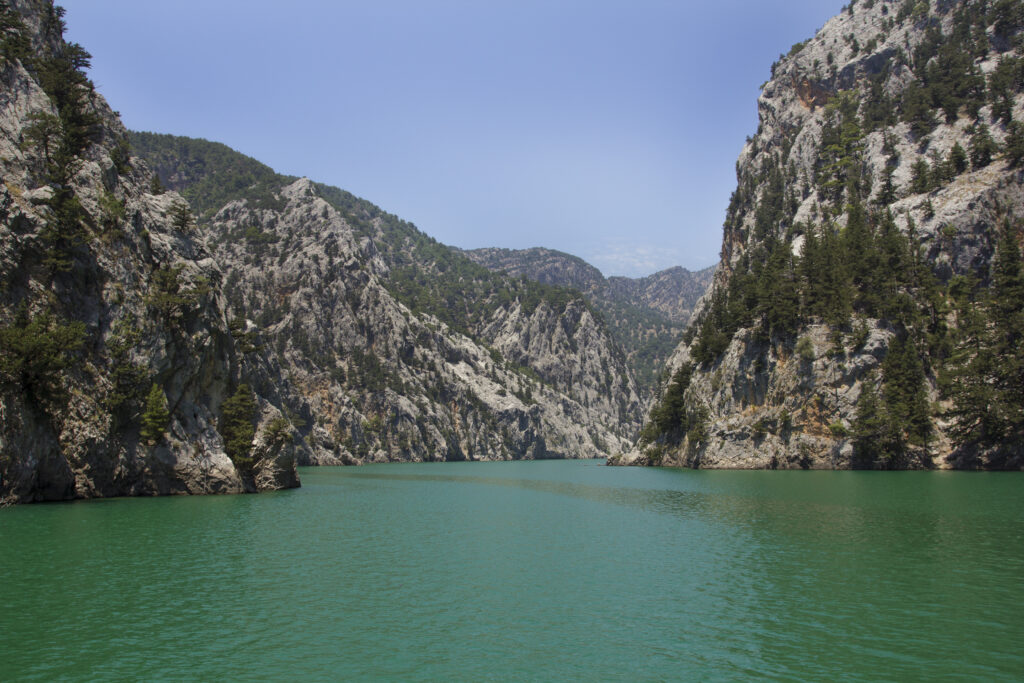 Stunning mountain landscape with rugged cliffs green trees and turquoise river winding valley Wallpaper