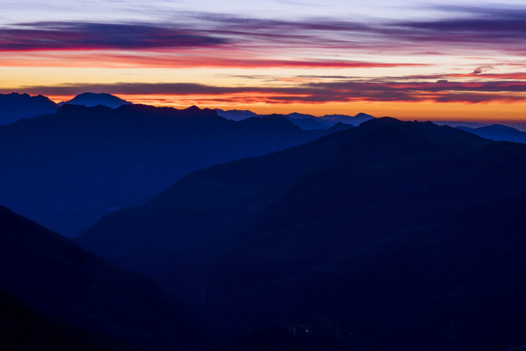 Mountain sunset wallpaper with indigo peaks and vibrant pink orange purple sky at dusk