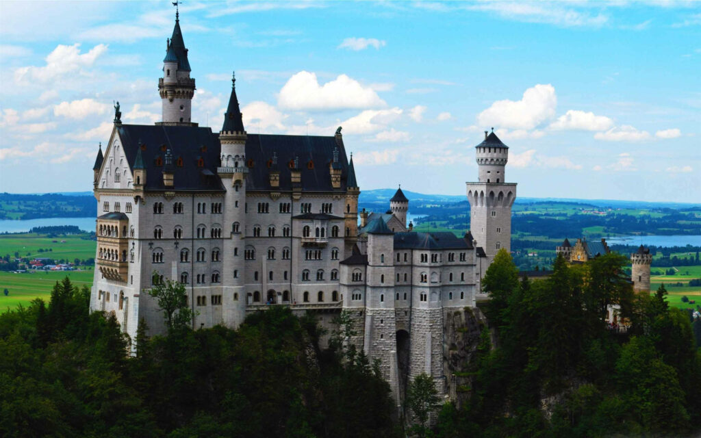 Serene Neuschwanstein Castle Wallpaper: Lush Greenery & Blue Sky