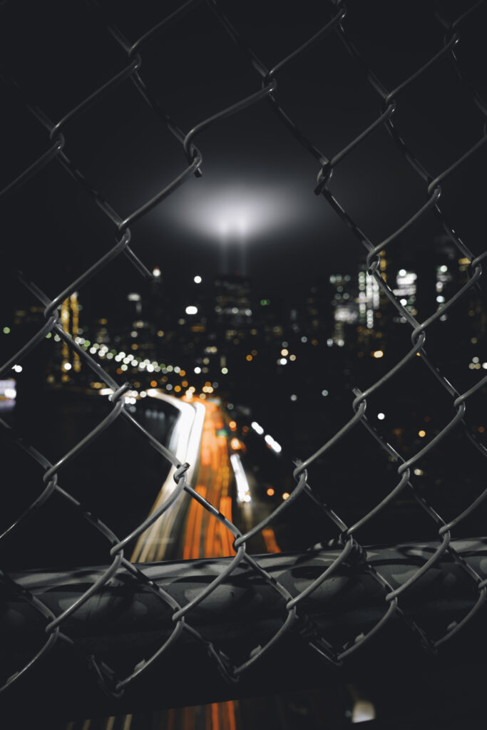 Stunning Night Cityscape Wallpaper Behind Mesh Fence - Urban Vibes