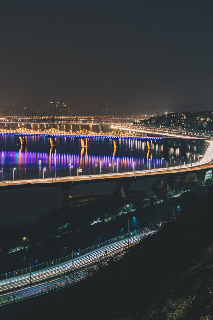 Vibrant Night Cityscape Wallpaper: Luminous Bridge & Reflective Water