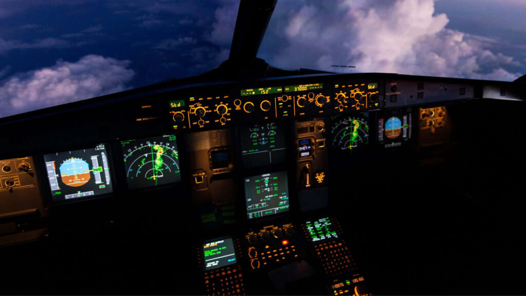 Nighttime aircraft cockpit view with illuminated instruments and glowing displays above clouds at dusk Wallpaper