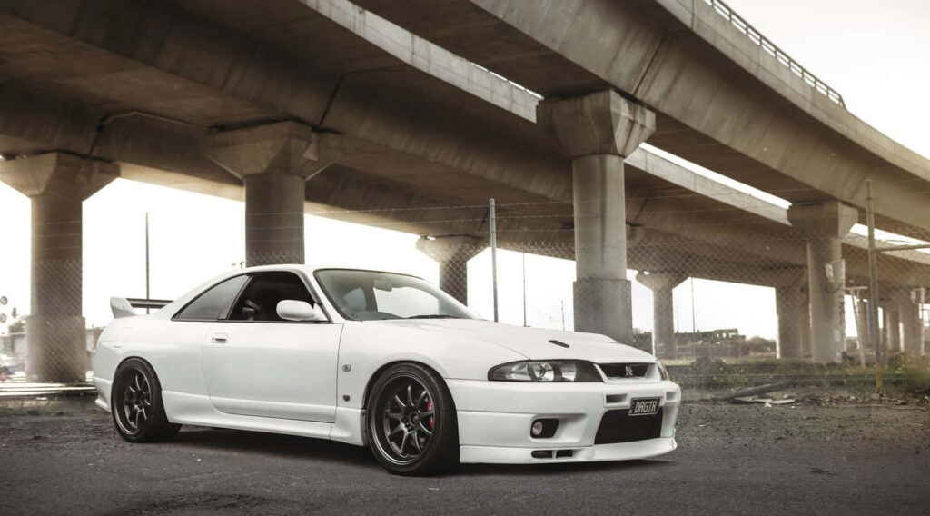 Elegant Nissan R33 GTR Wallpaper: Urban Performance Under Bridge