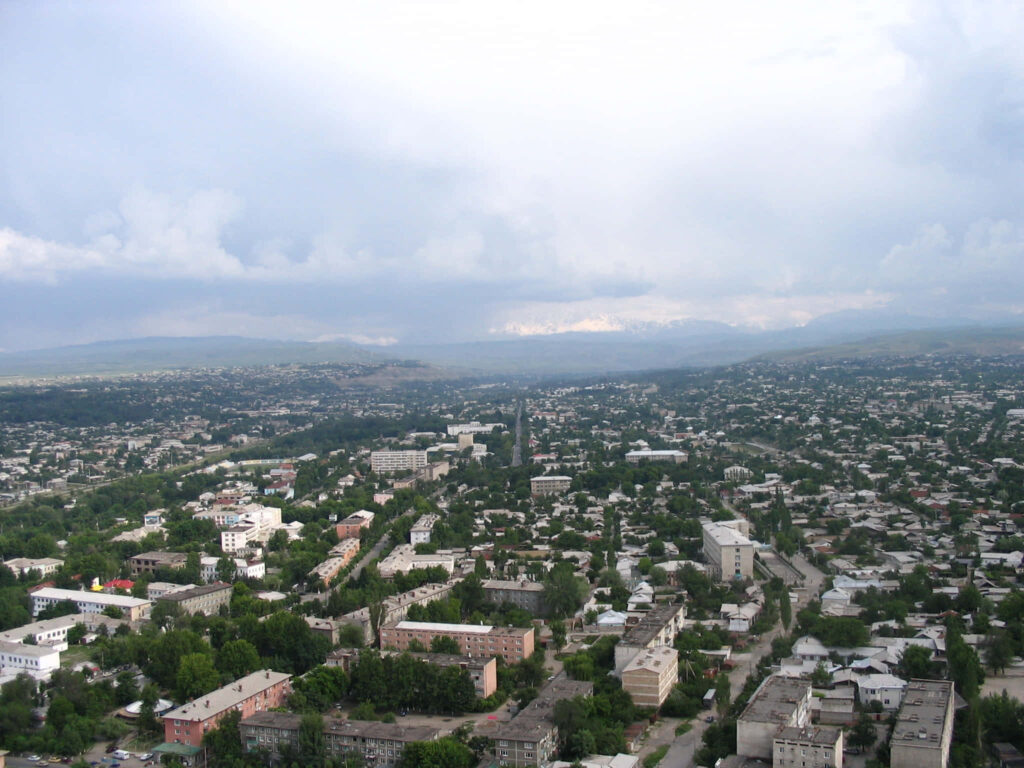 Stunning Osh Cityscape Wallpaper: Greenery, Homes & Mountains