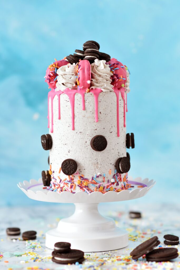 Beautiful Pink Icing Cake with Sprinkles & Cookies on Blue Background Wallpaper