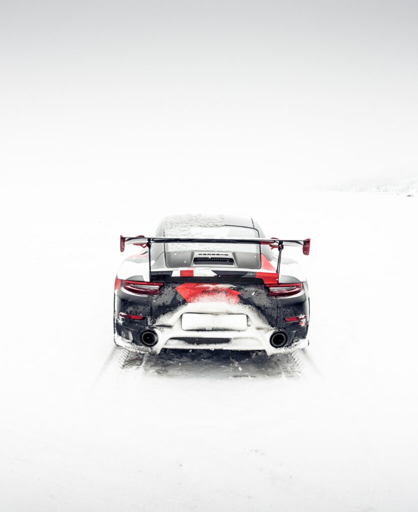 Rear View of Sleek Sports Car on Snowy Off-Road Terrain Wallpaper