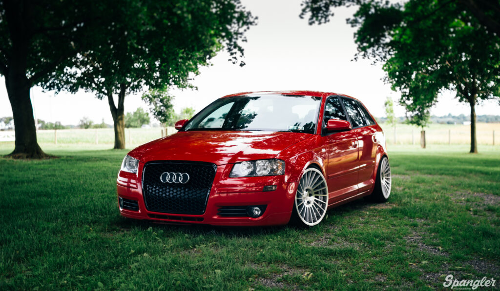 Red Audi A3 Front View Wallpaper on Lush Green Landscape