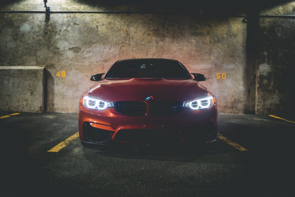 Red BMW 320i Front View in Dramatic Parking Area Wallpaper