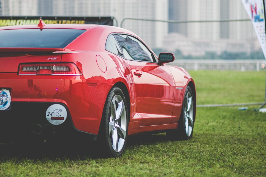 Striking Red Chevrolet Sports Car Wallpaper in Scenic Outdoor Setting