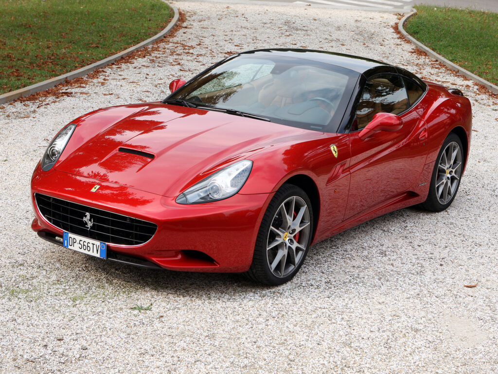 Stunning Red Ferrari California Side View Wallpaper on Gravel Background