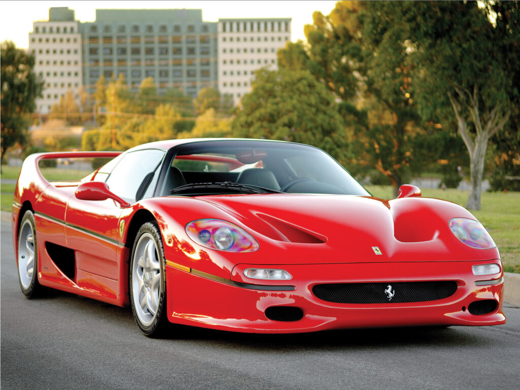 Stunning Red Ferrari F50 Wallpaper: Front View with Urban Greenery