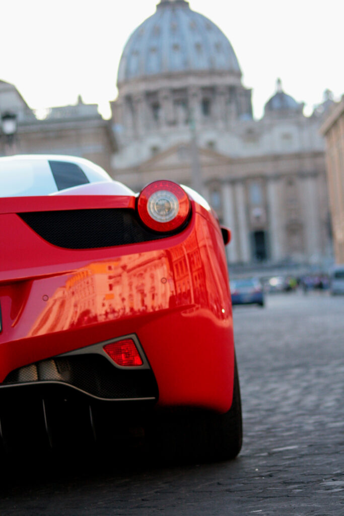 Stunning Red Ferrari with Sleek Tail Light Against Architectural Backdrop Wallpaper