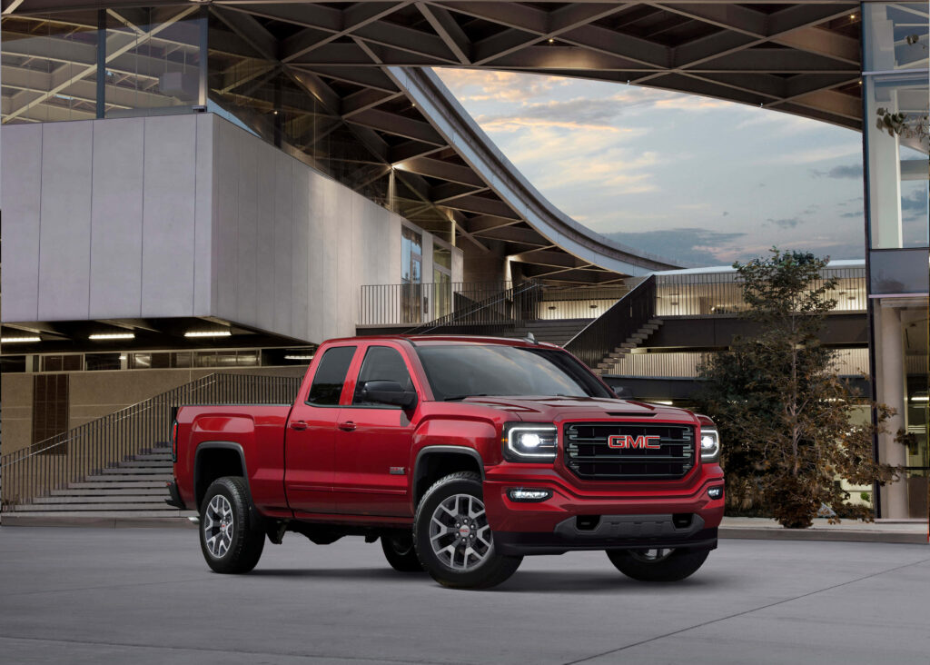 Powerful Red GMC Sierra Wallpaper Against Modern Architecture
