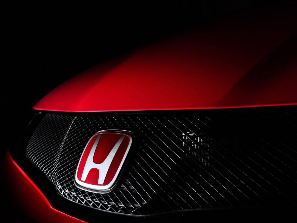 Close-up of red Honda logo on dark diamond-mesh grille and deep red car hood automotive wallpaper