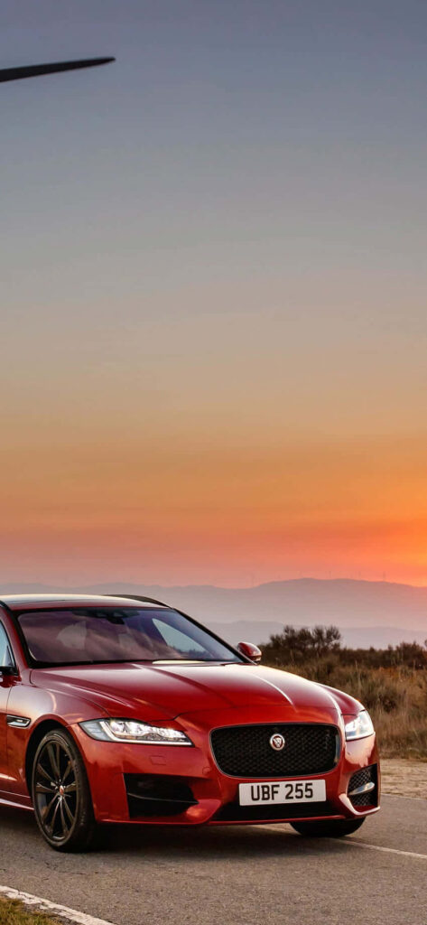 Elegant Red Jaguar Wallpaper Against Serene Sunset Background
