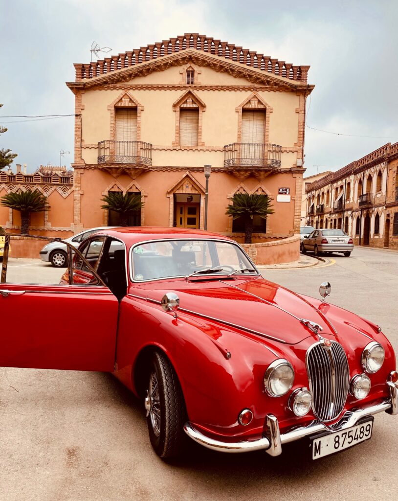 Stunning Red Retro Jaguar Car Against Historic Building Background Wallpaper