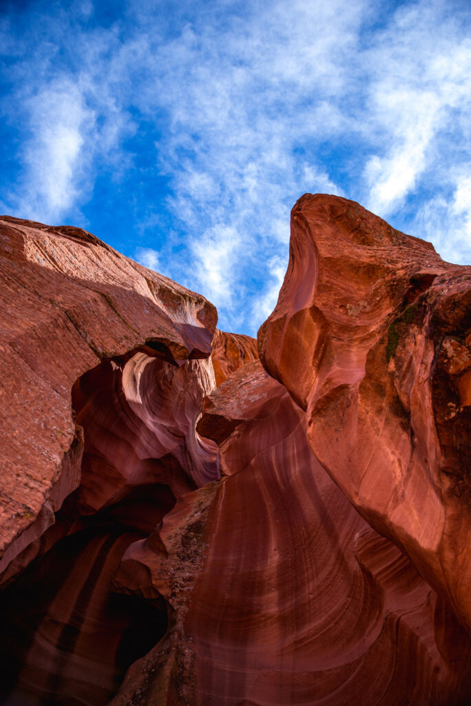 Bottom view of red rock canyon with layered sediment patterns under vivid blue sky clouds Wallpaper