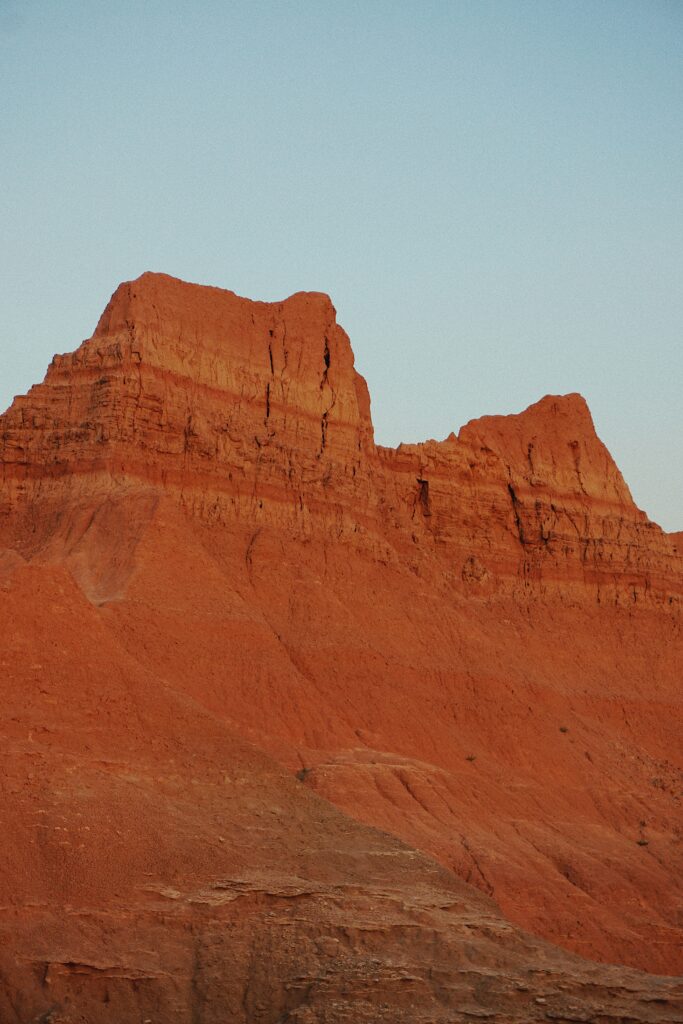 Striking red rock canyon landscape with rugged slopes and clear blue sky wallpaper background