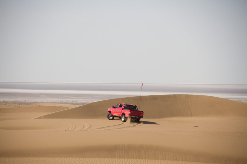 Adventure Awaits: Red SUV in Desert Landscape Wallpaper