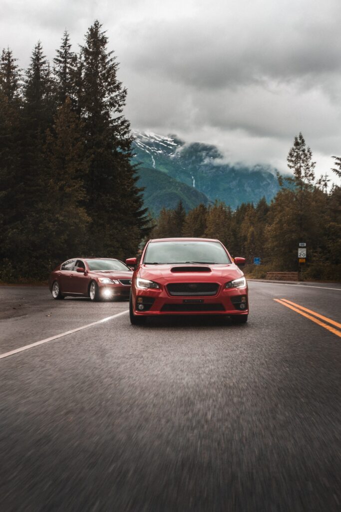 Stunning Red Subaru on Winding Road: Lush Green Mountainscape Wallpaper