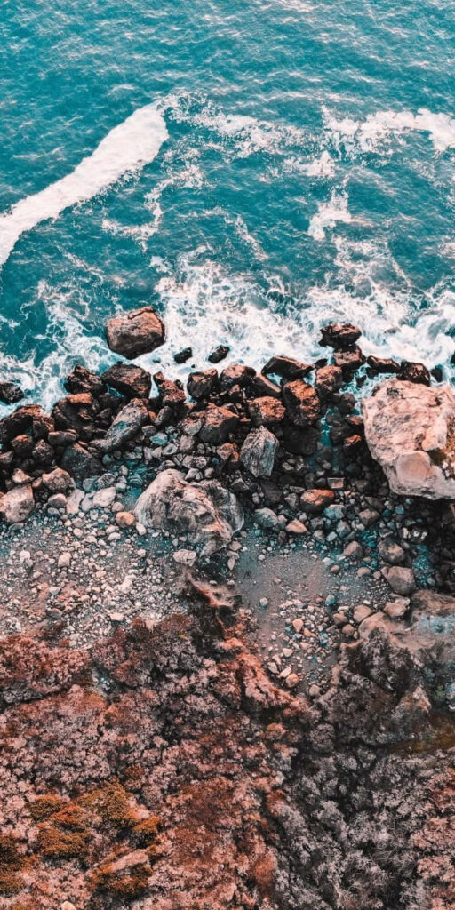 Stunning Rocky Beach Wallpaper: Waves & Earthy Tones - Phone Background