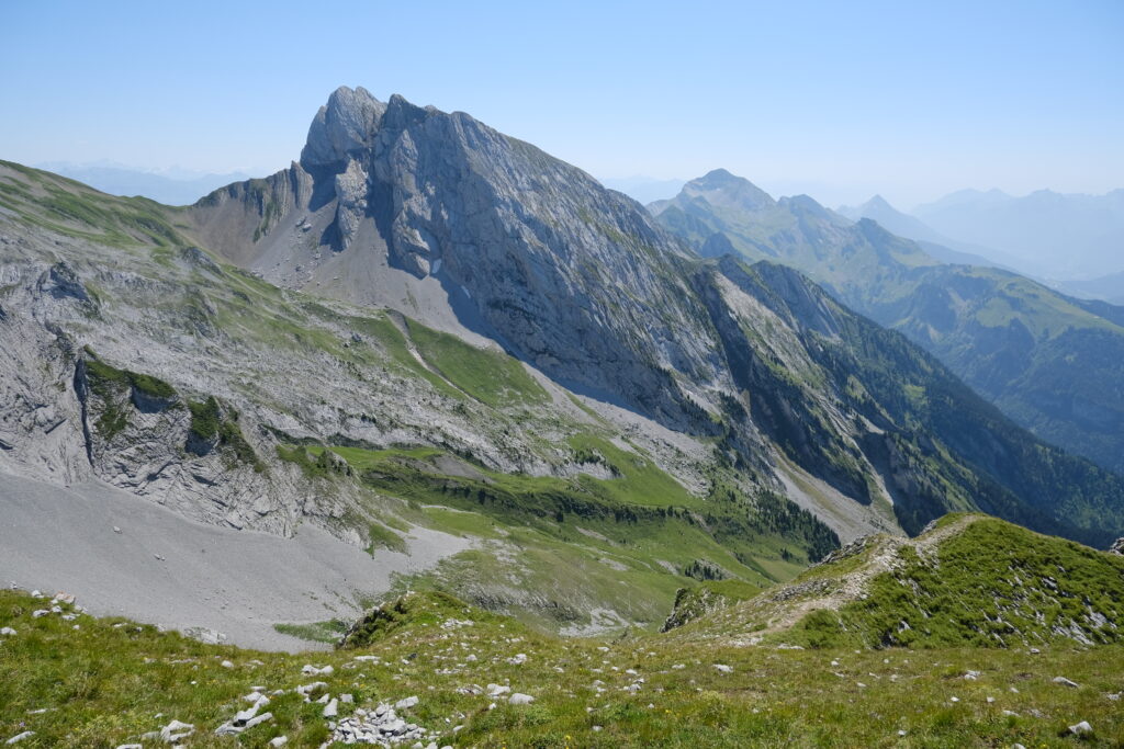 Rocky mountain landscape with green grass slopes under clear blue sky high resolution wallpaper