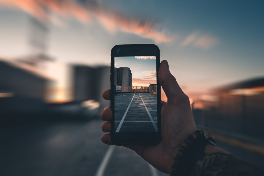 Artistic Wallpaper: Hand Holding Smartphone with Rooftop Sunset View