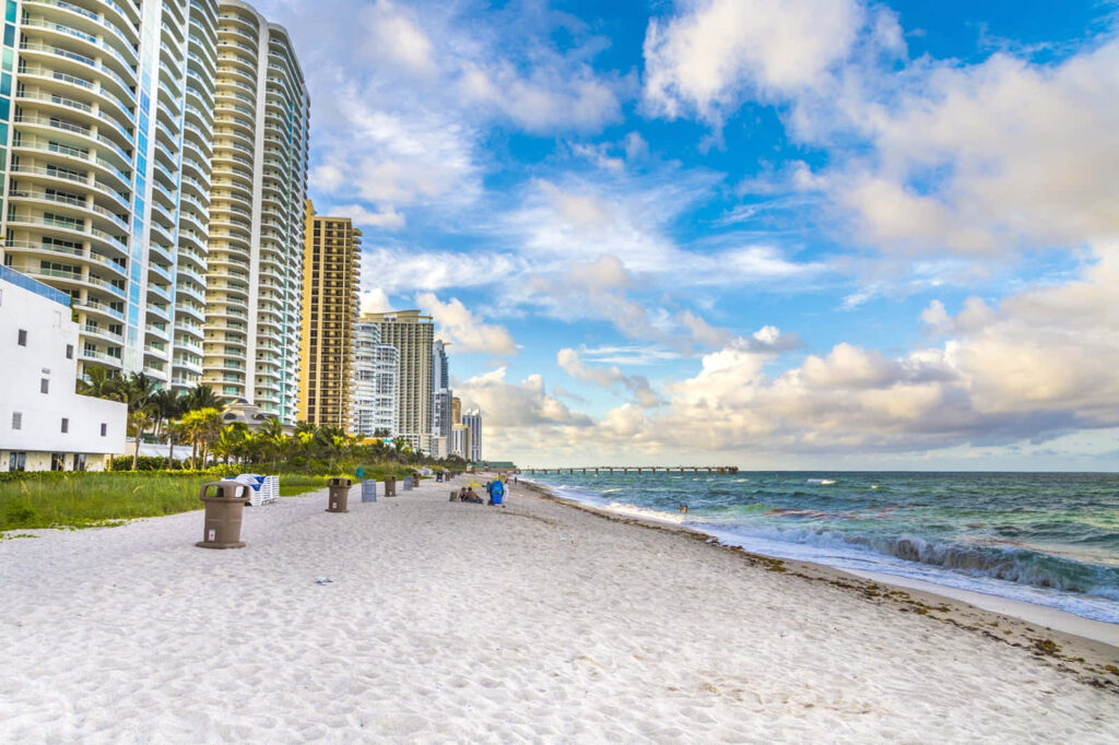 “Seaside Wallpaper: Sandy Beach & High-Rise Buildings Under Blue Sky”