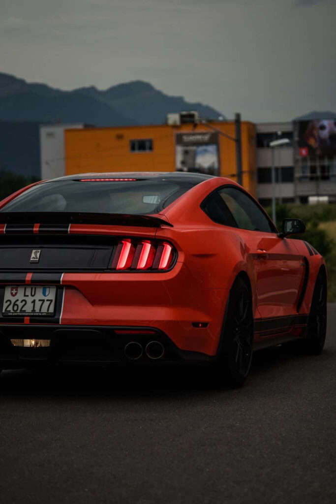 Sleek Shelby Mustang Wallpaper: Bold Orange Beauty & Urban Mountains