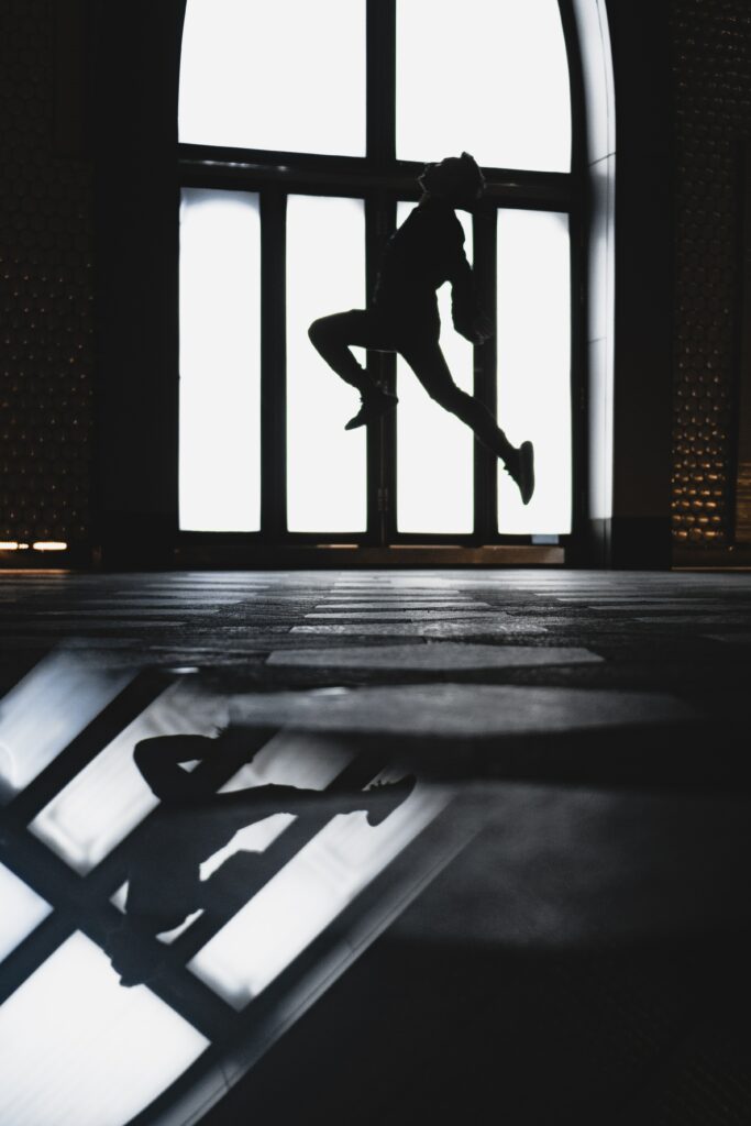 Captivating Silhouette Wallpaper: Dynamic Jump Against Arched Window