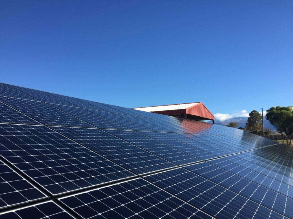 Lateral View of Solar Panel Installation with Blue Sky & Greenery Wallpaper