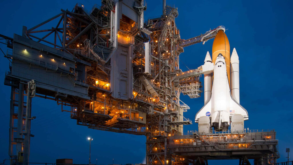 Vibrant Space Shuttle Wallpaper: Illuminated Launch Pad Night Sky