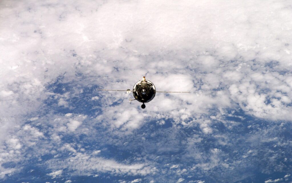 Stunning Spacecraft Wallpaper: Orbiting Earth with Fluffy Clouds