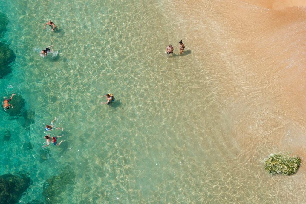 Sunlit Beach Aerial View: Crystal Clear Waves & Sandy Shores Background Wallpaper