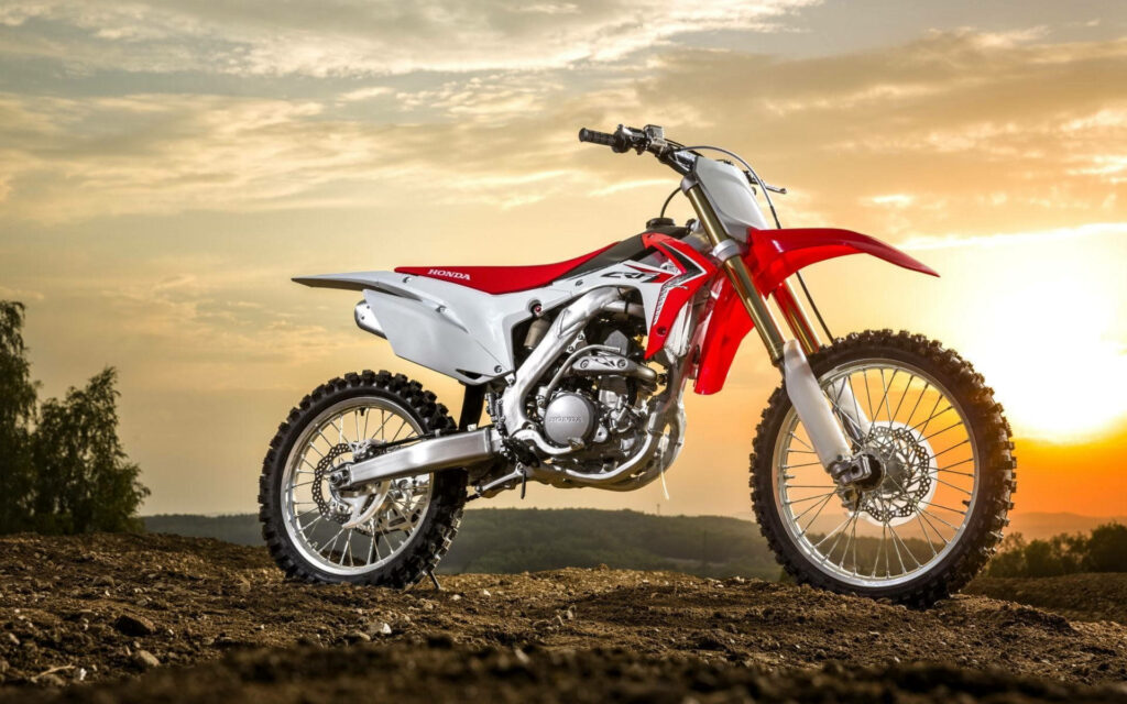 Epic Sunset Motocross Bike Wallpaper on Rugged Terrain