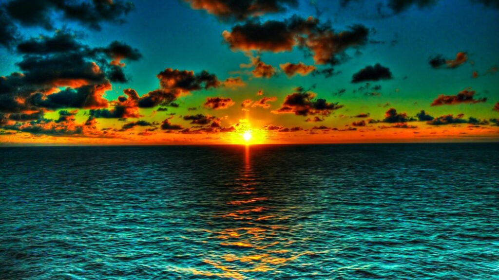 Stunning vibrant sunset over turquoise sea with dramatic clouds and golden orange horizon light Wallpaper