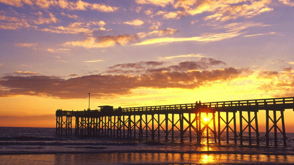 Stunning Sunset Over Ocean: Vibrant Orange & Purple Pier Reflection Wallpaper