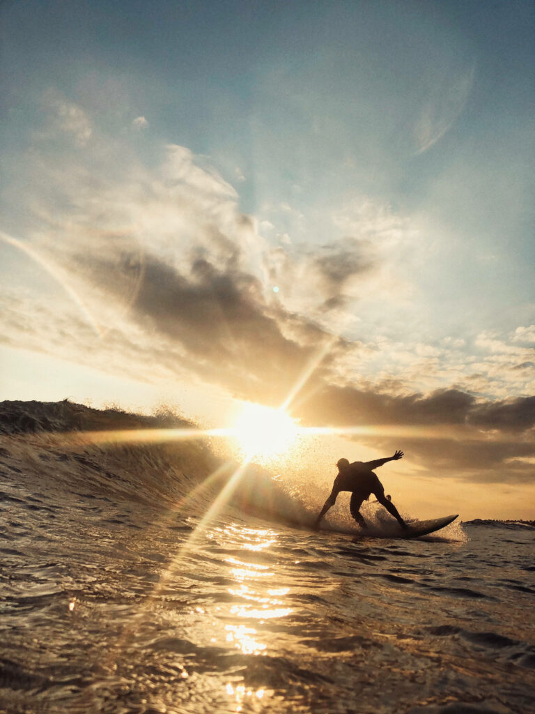 Stunning Sunset Surfing Wallpaper: Surfer Riding Waves at Dusk