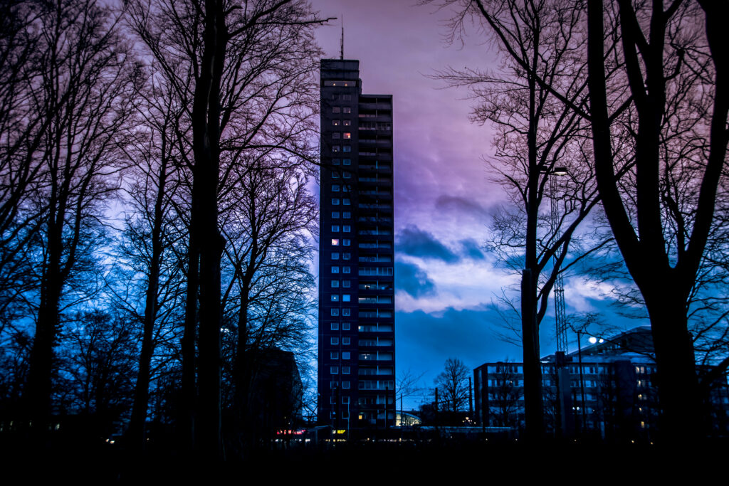 Stunning Sweden Wallpaper: Tall Building & Leafless Trees at Sunset
